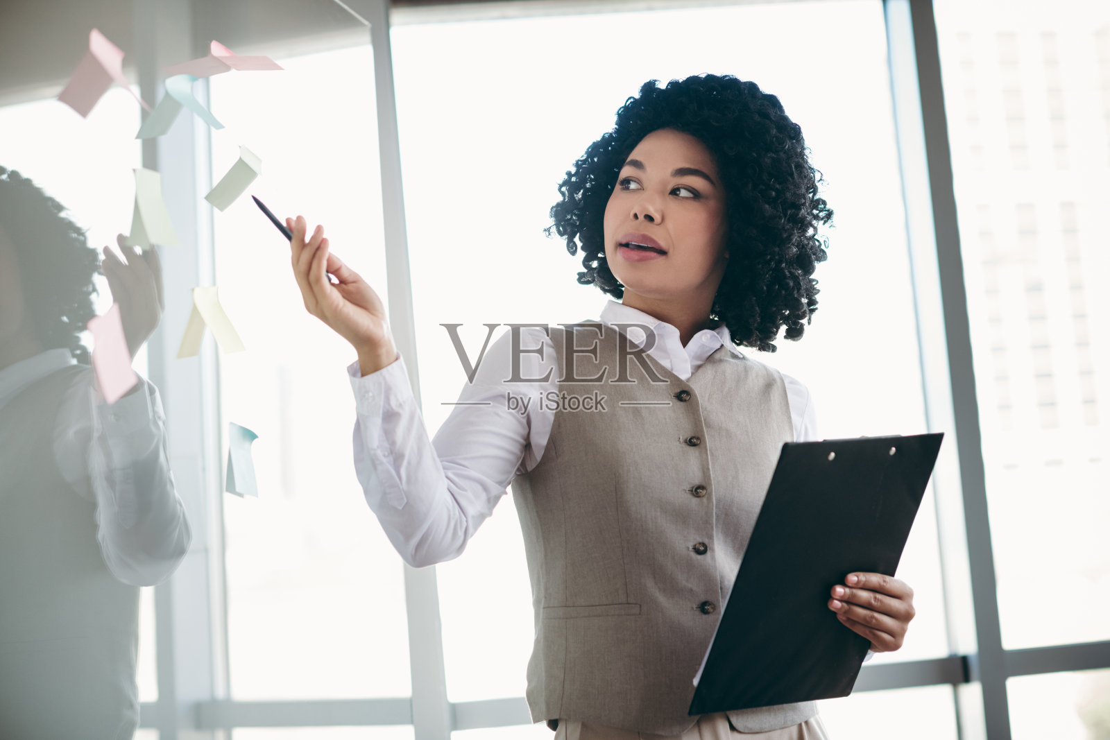 自信的商务专业人士在时尚的办公室环境中通过便利贴展示想法。照片摄影图片