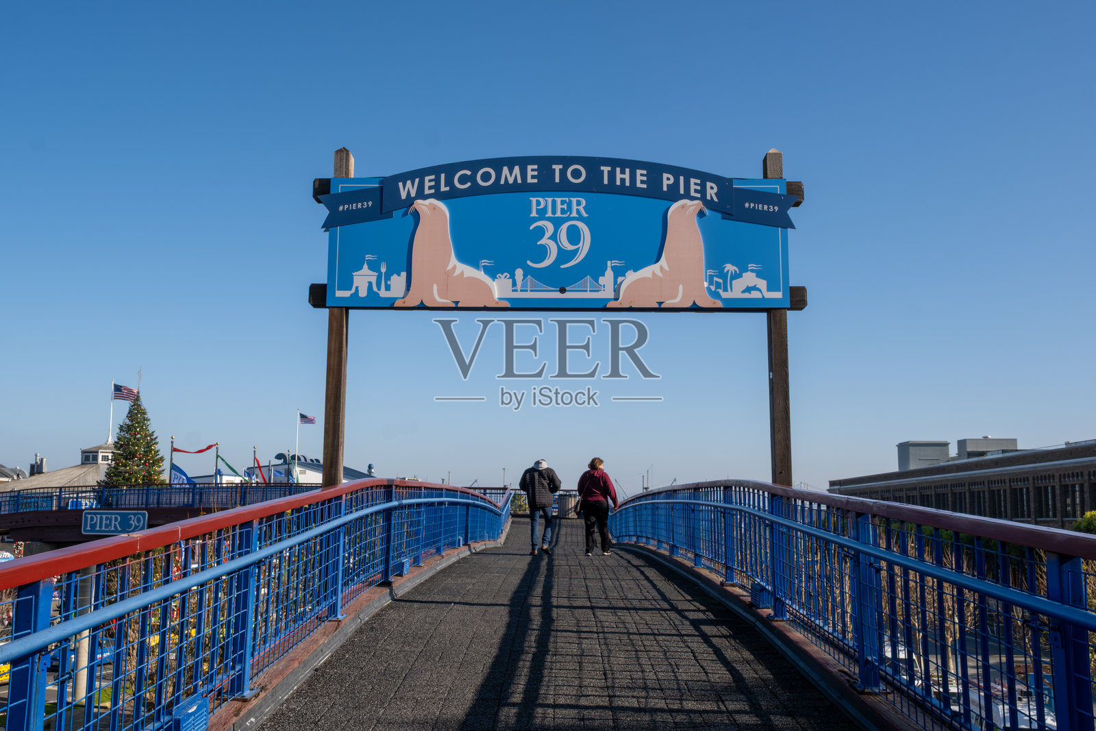 游客在阳光明媚的日子里走向39号码头的欢迎标志。照片摄影图片