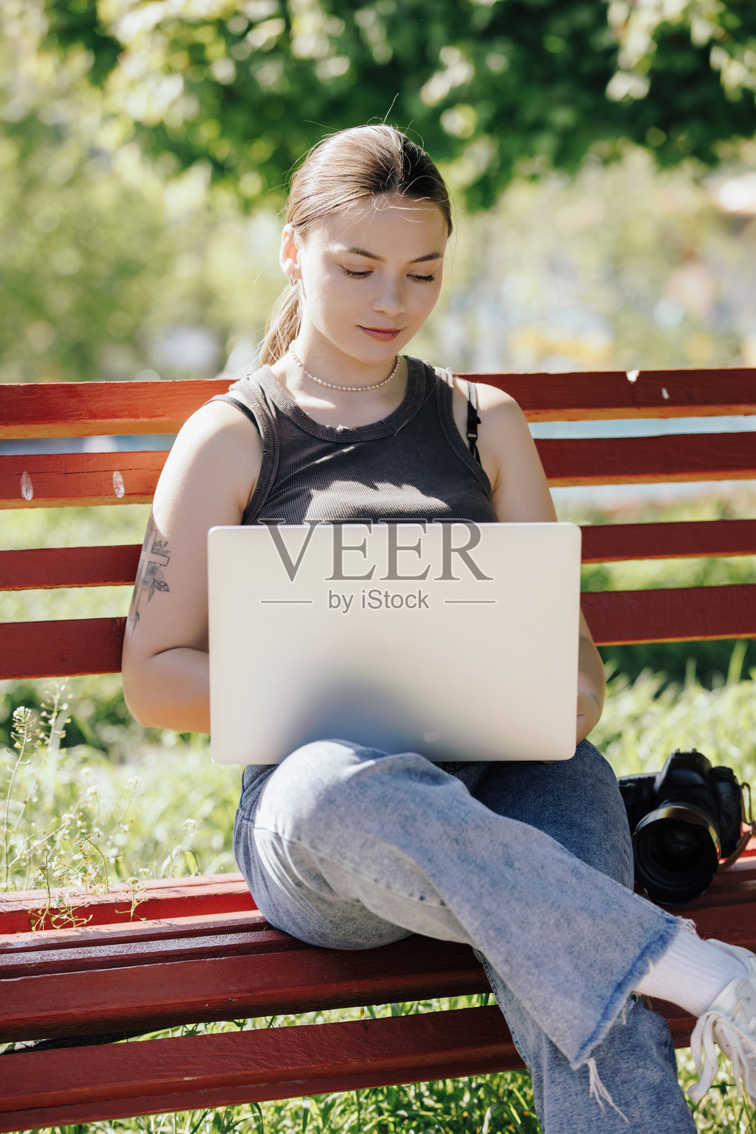 坐在长椅上使用笔记本电脑的女性摄影师照片摄影图片