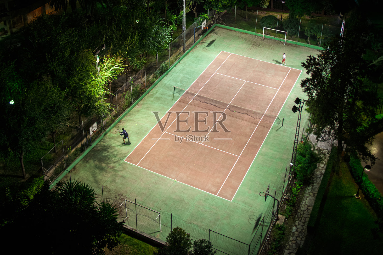 在昏暗的塞维利亚球场进行的户外夜间网球比赛照片摄影图片