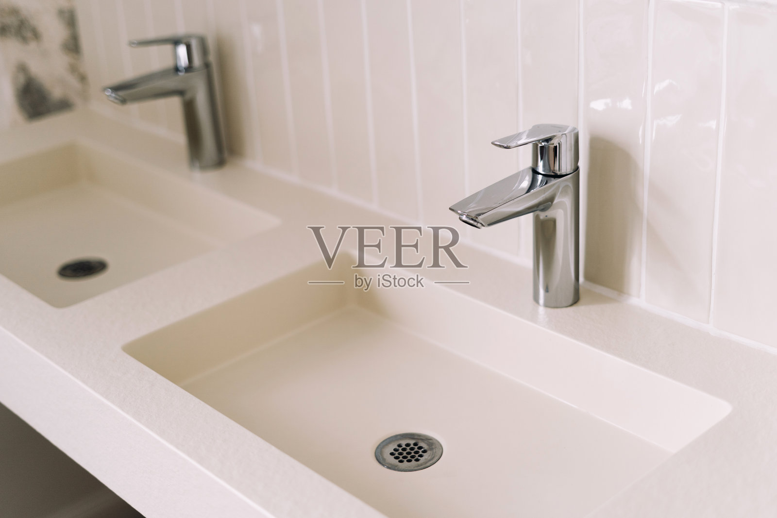 明亮通透的浴室展示了两个现代化的洗手盆，配有抛光铬水龙头。照片摄影图片