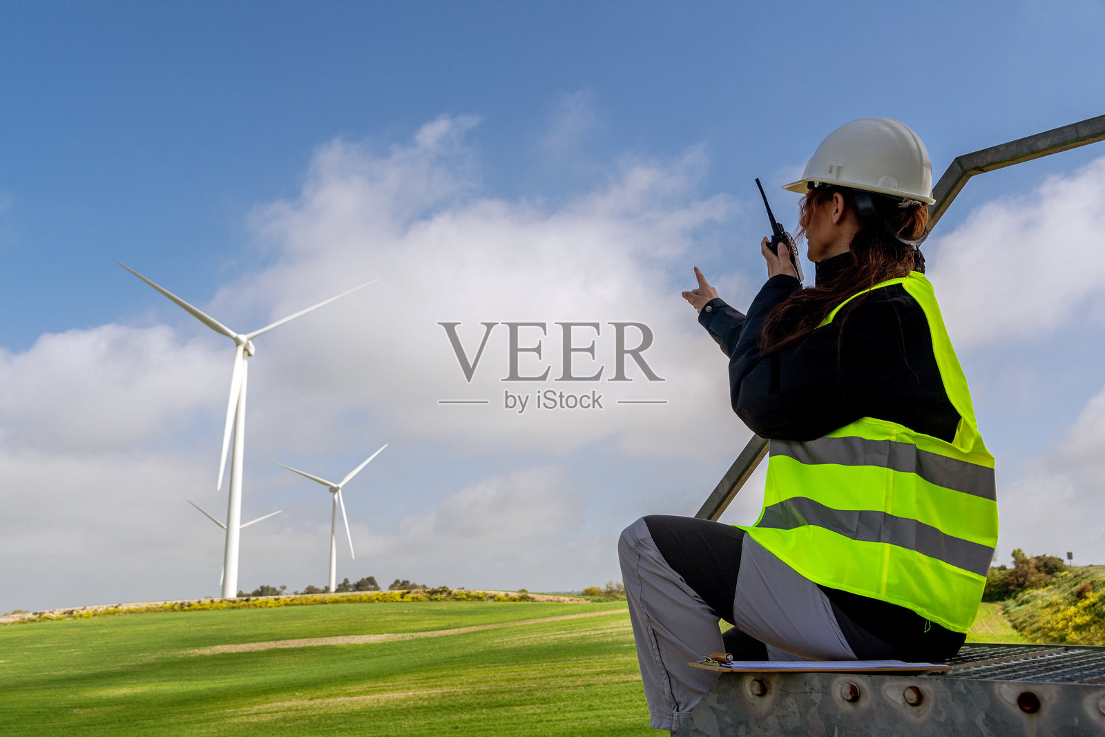 女性工程师在风力发电场使用对讲机进行沟通照片摄影图片