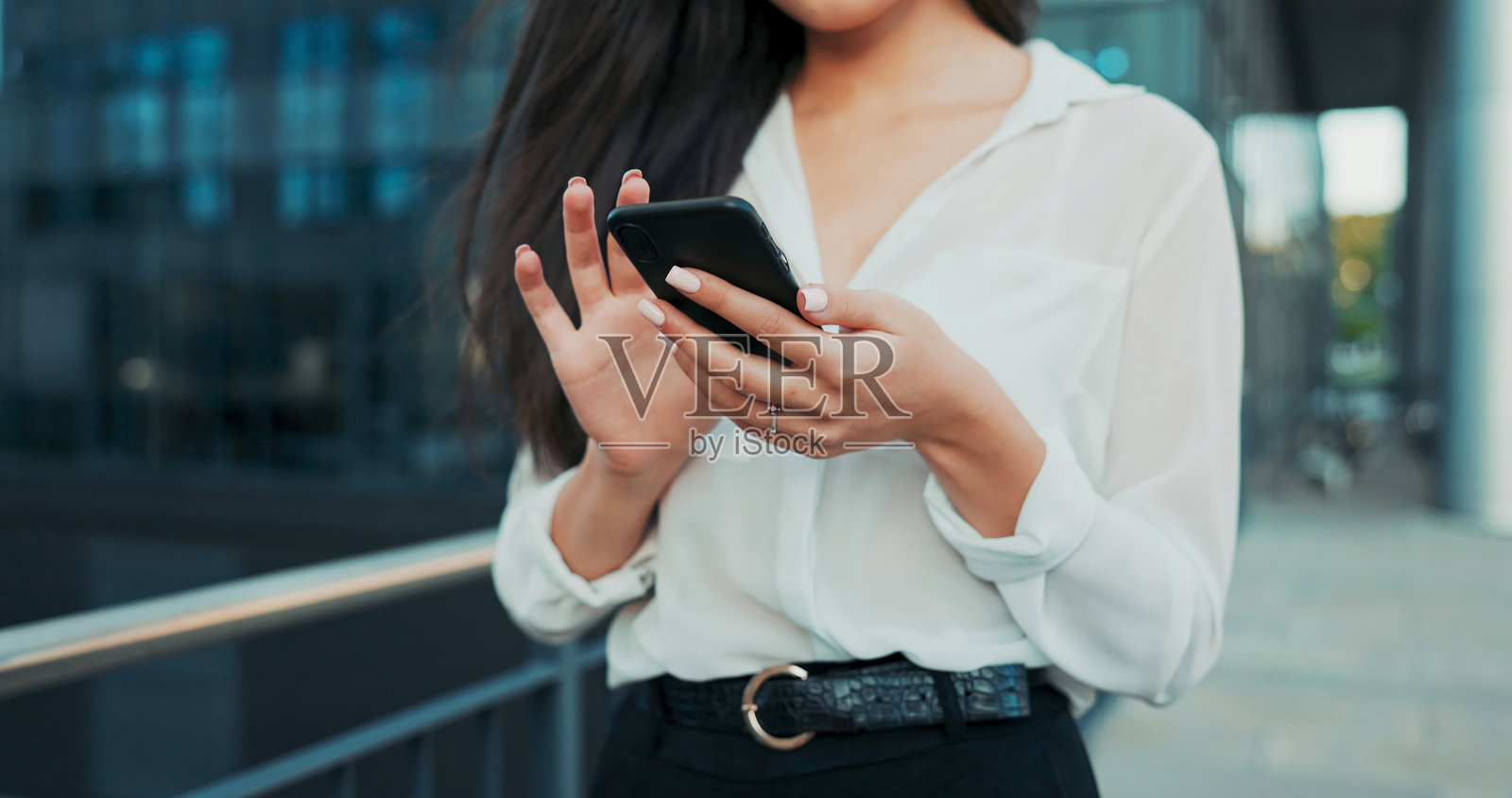 优雅女性的整洁手部特写，手持手机，轻触屏幕发送信息。照片摄影图片