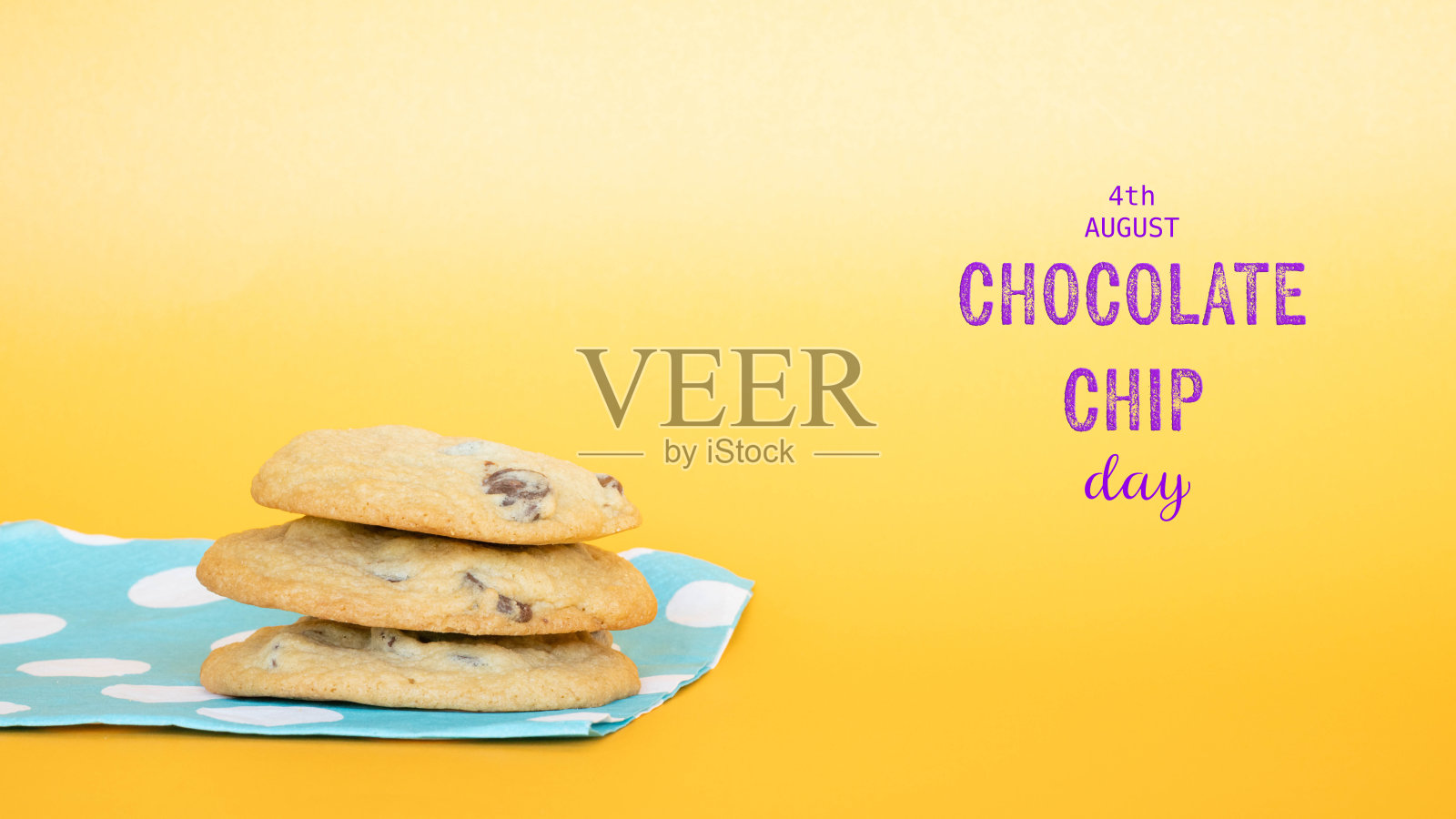 8月4日，巧克力曲奇饼干日，配有新鲜出炉的金黄色巧克力曲奇饼干，放在蓝白波点纸餐巾上，背景为黄色。照片摄影图片