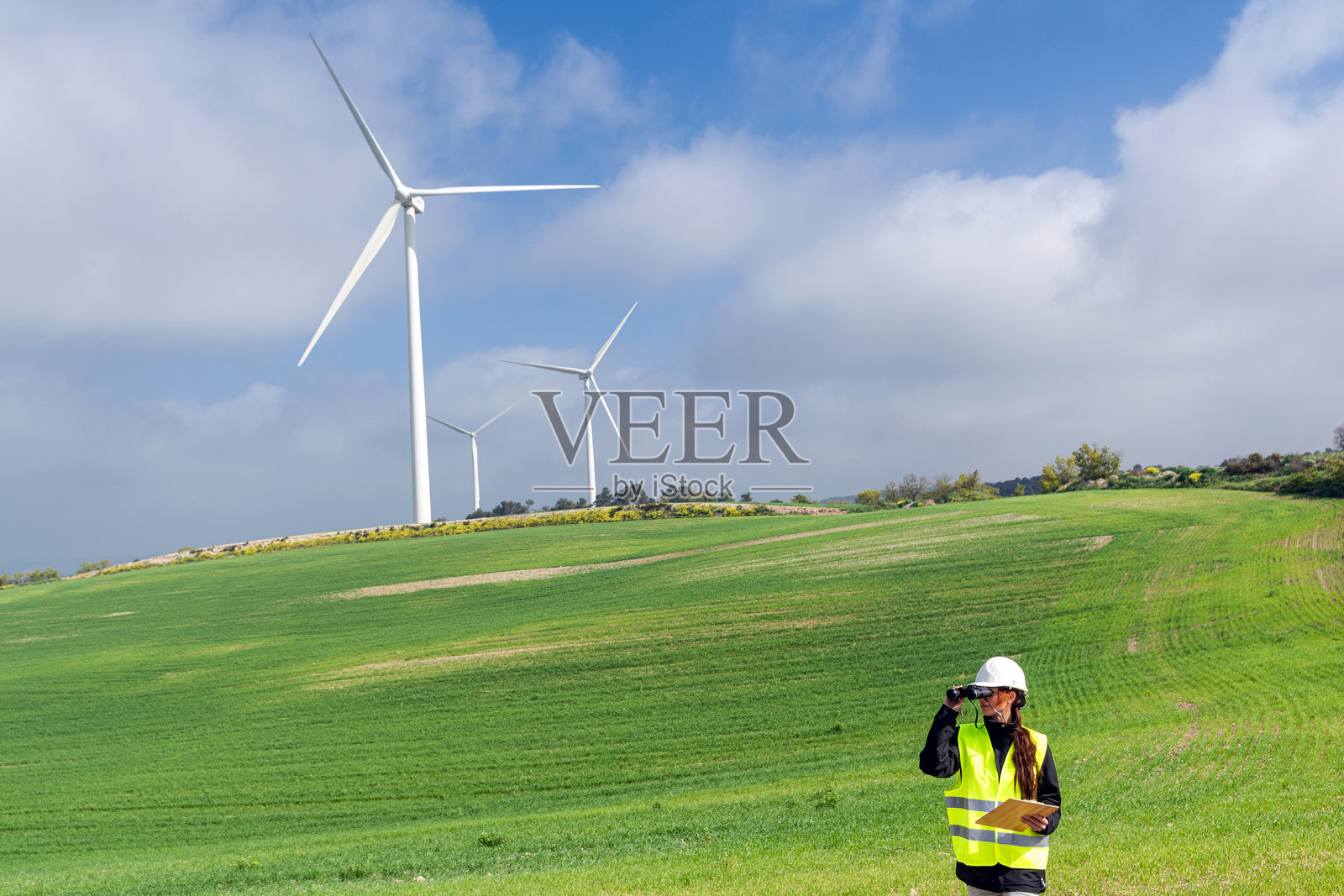 女性工程师在绿色田野中检查风力涡轮机照片摄影图片
