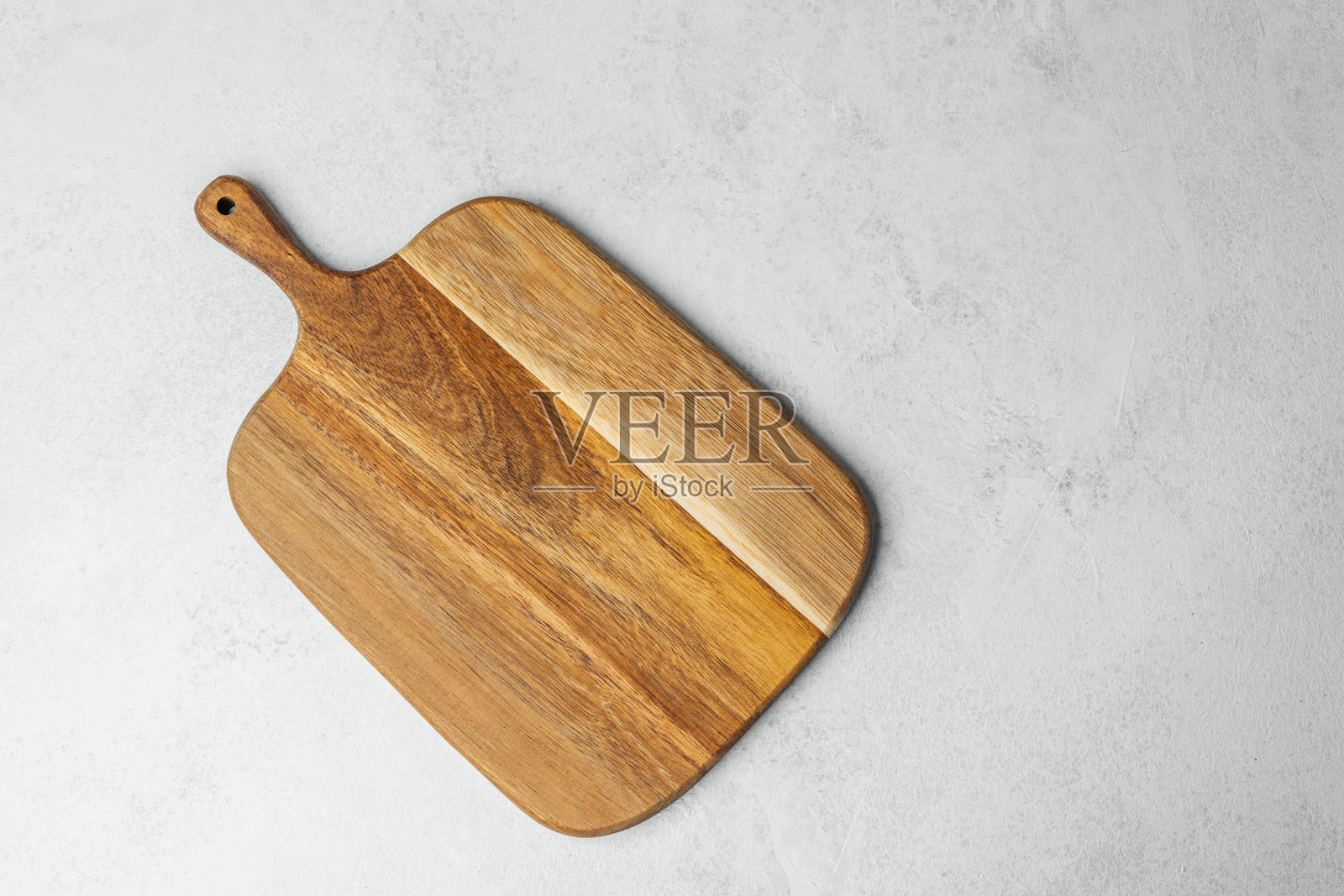 木质切菜板放在浅灰色表面上，准备进行餐前准备。照片摄影图片