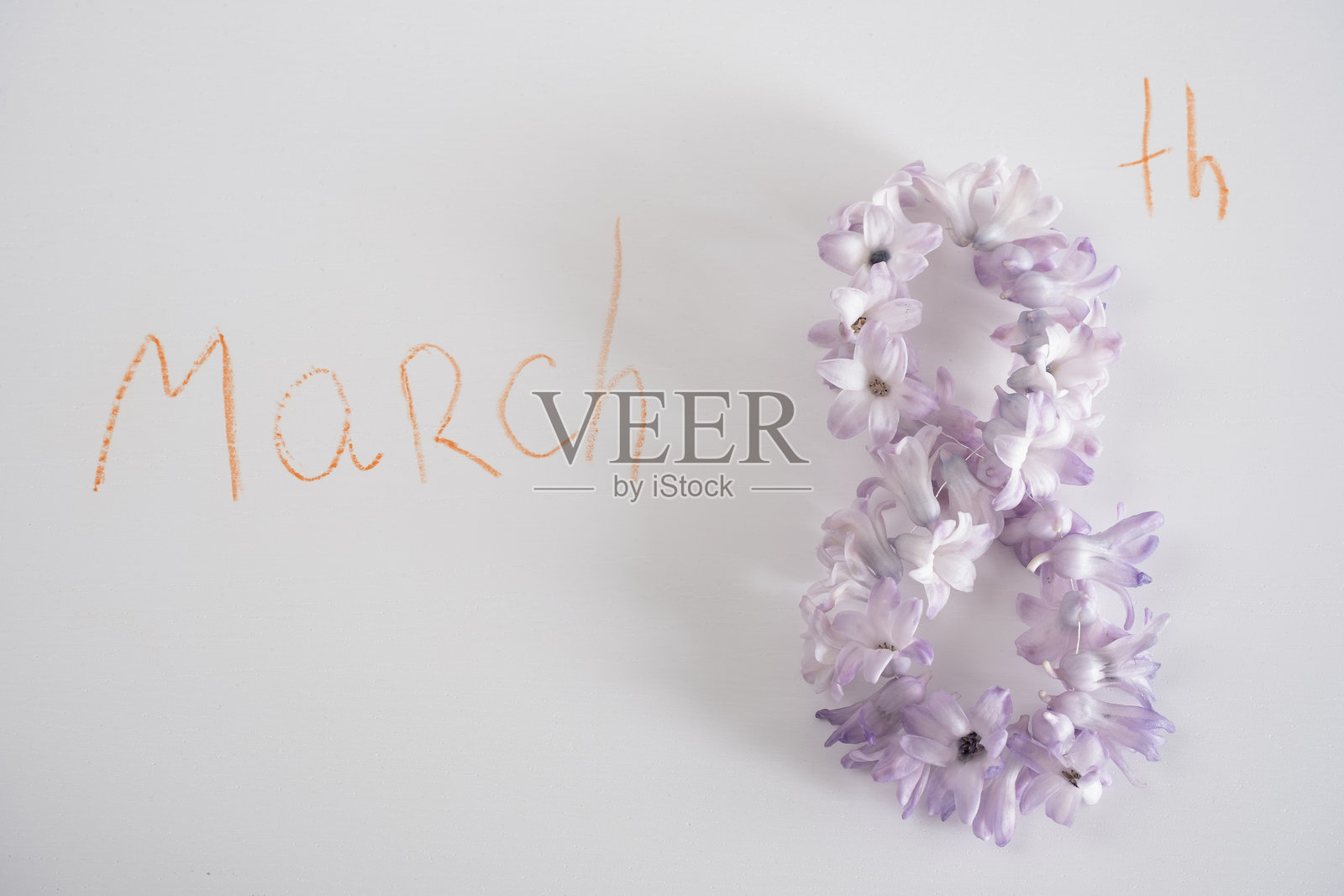 庆祝3月8日国际妇女节的创意花卉作品。精致的紫丁香风信子以数字八的形状排列，橙色的“March”字样写在旁边。照片摄影图片