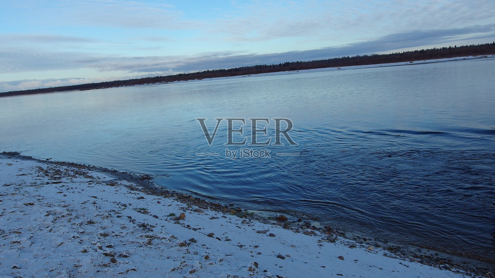 被雪覆盖的土地环绕的水体。照片摄影图片