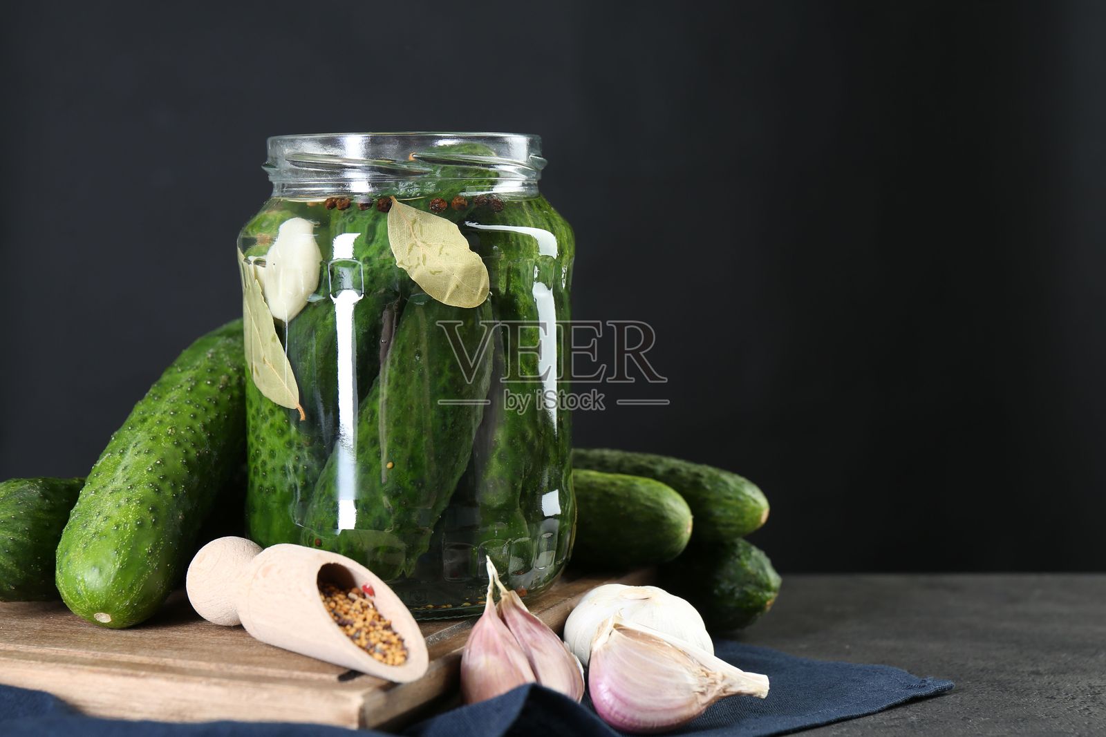 腌制泡菜。新鲜黄瓜和香料放在灰色桌子上的罐子里。留有文字空间。照片摄影图片