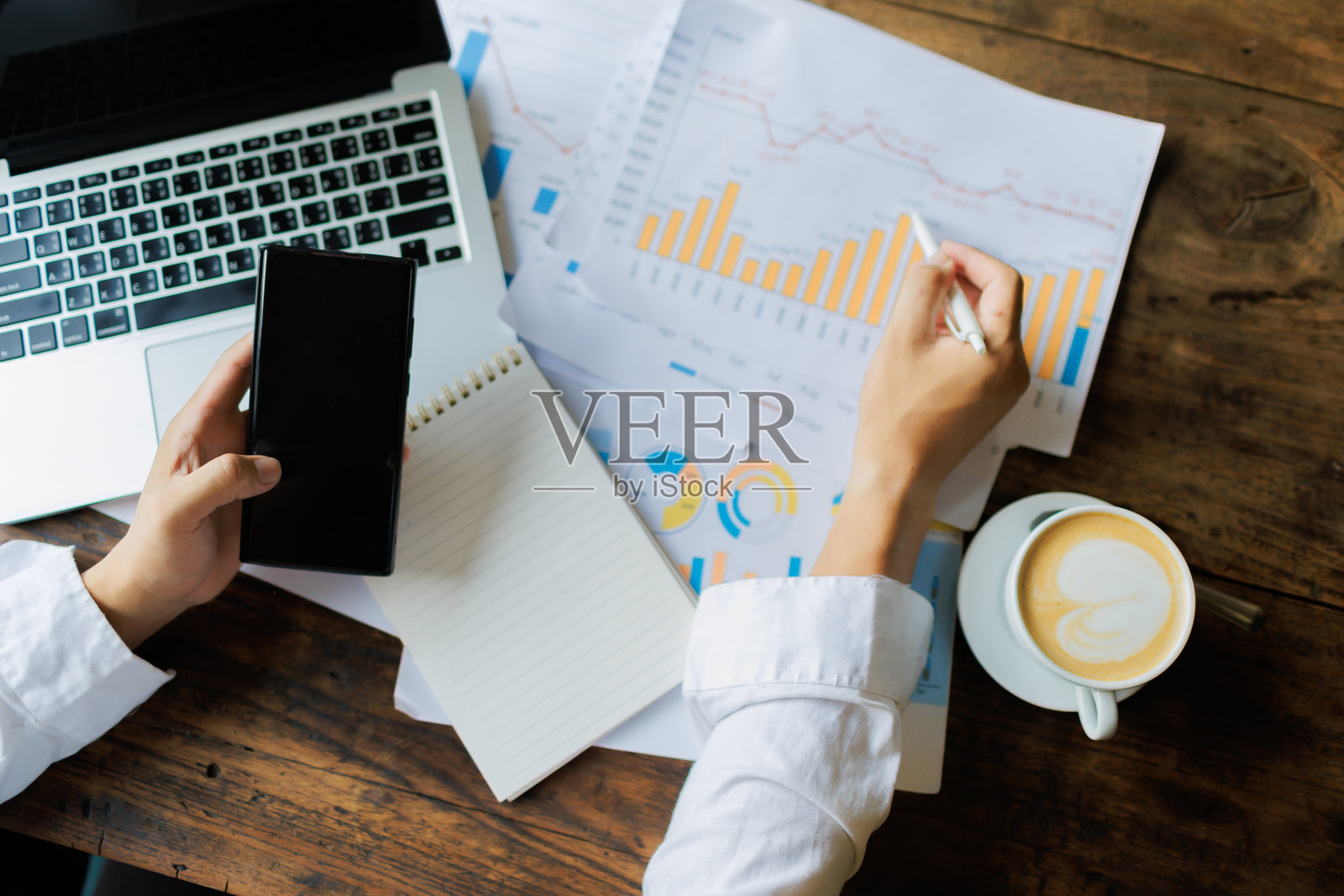 在散落的文件中，一名员工的决心和勤奋熠熠生辉，努力追求公司年度审查报告的完美准确性。照片摄影图片