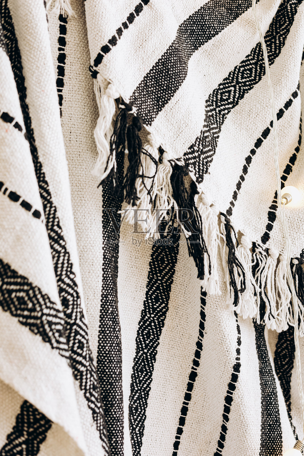 手工编织的纺织品，具有几何图案和流苏边缘，展示在舒适的环境中照片摄影图片