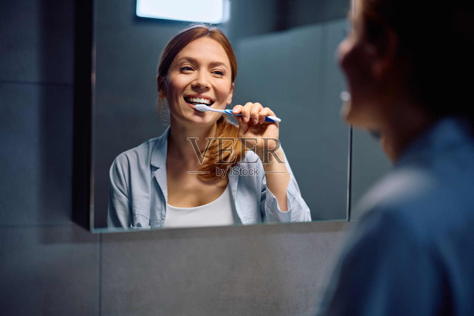 快乐的女人在镜子前刷牙。照片摄影图片