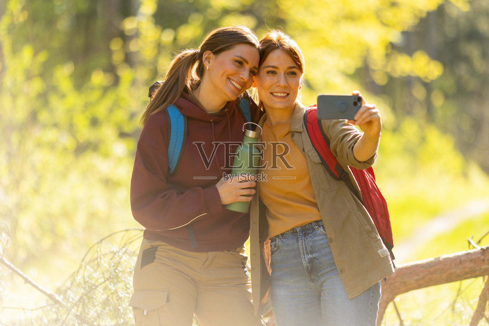 朋友们在阳光明媚、充满冒险的生机盎然的春季森林中捕捉快乐时刻照片摄影图片