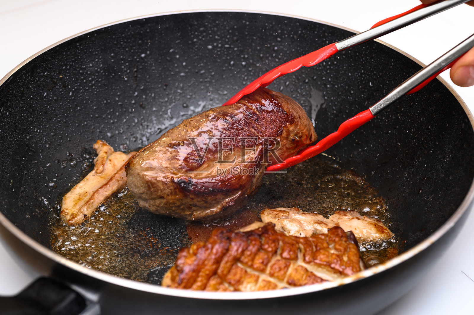 厨师翻转炸肉，金黄酥脆的鸭胸肉照片摄影图片
