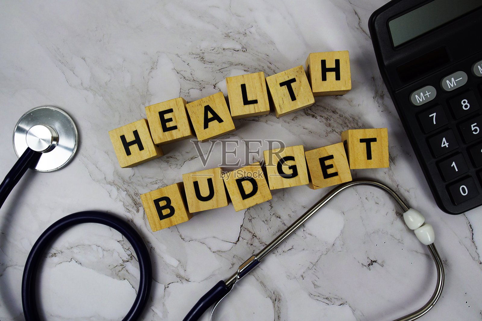 健康预算与木块字母、听诊器和计算器在大理石背景上照片摄影图片
