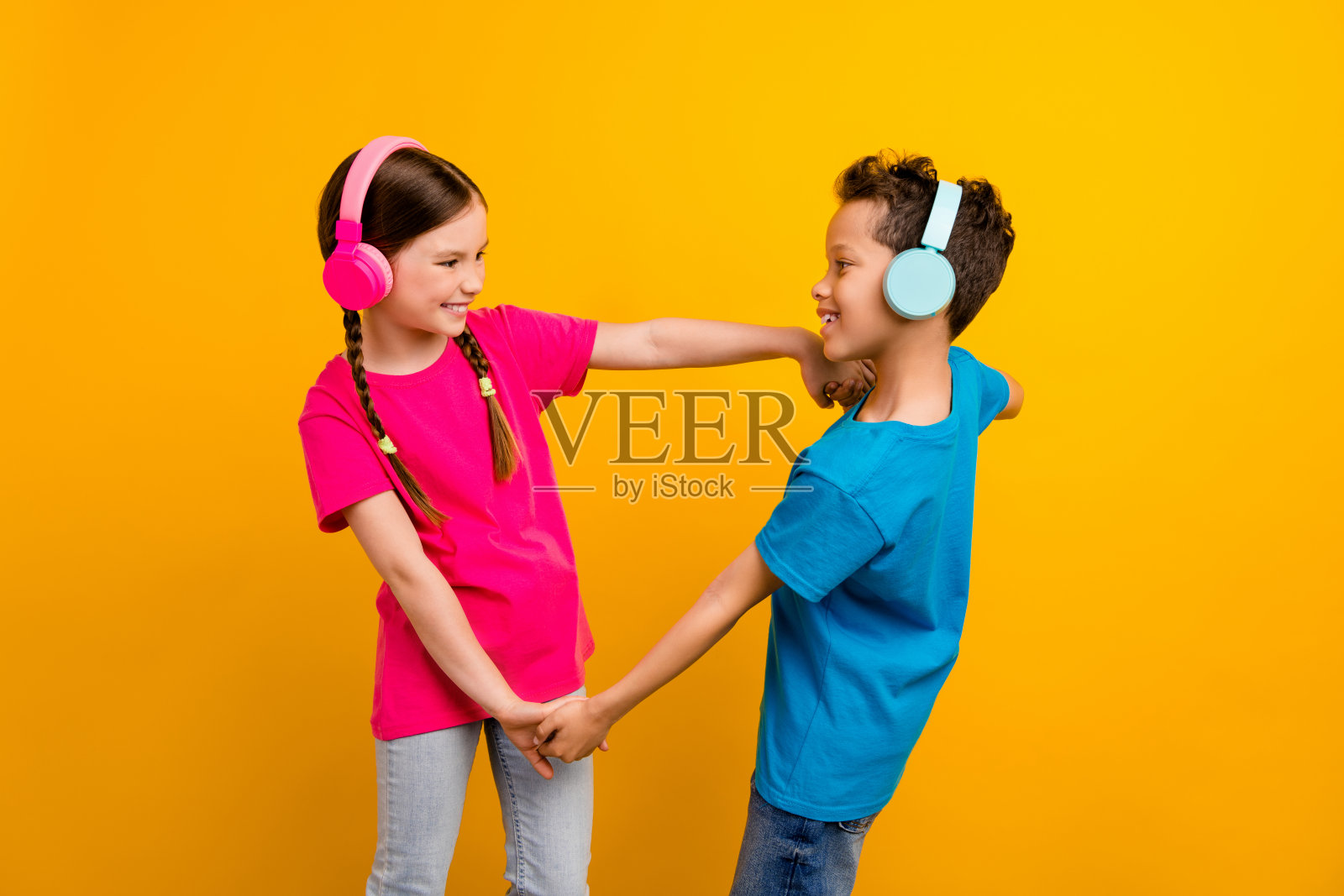 可爱的学龄前儿童穿着T恤在黄色背景下跳舞享受音乐照片摄影图片