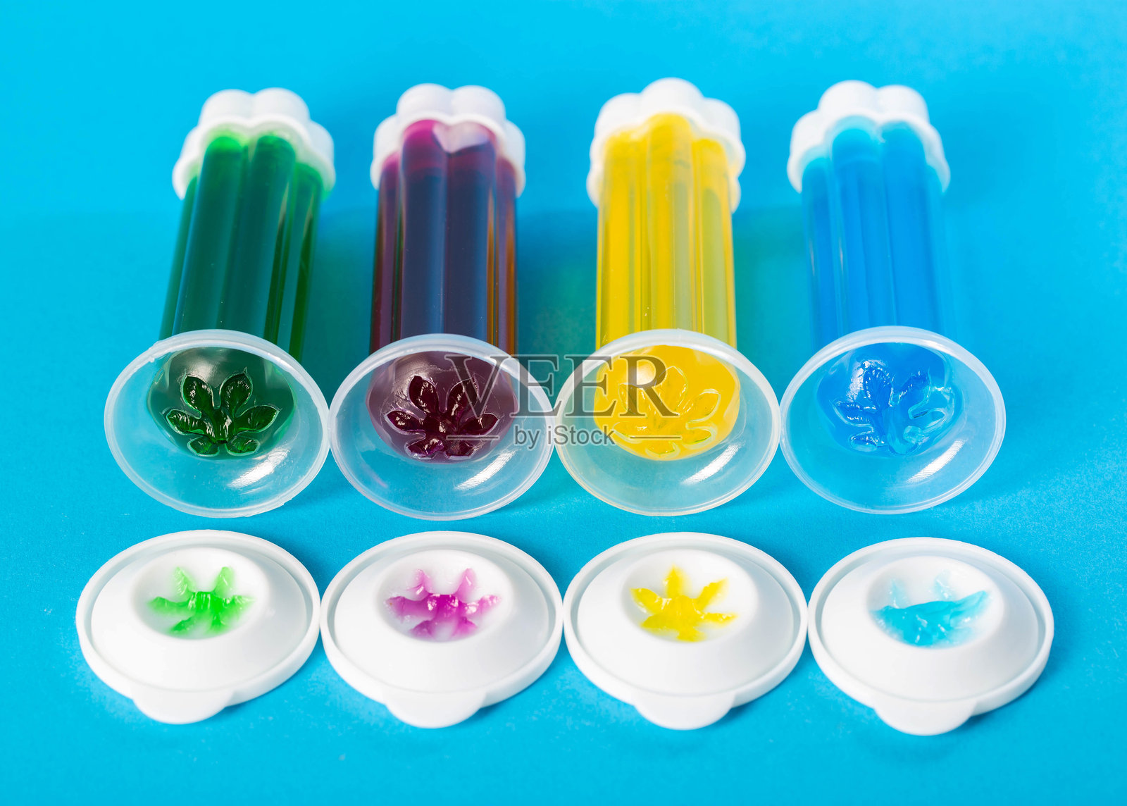 一组多色凝胶注射器，背景为蓝色，旁边有消毒剂和厕所清洁剂，特写镜头照片摄影图片