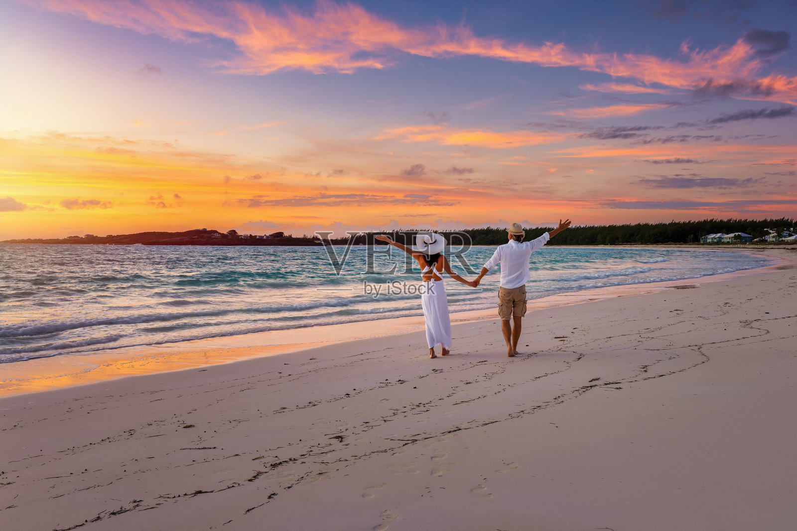 一对快乐的假日情侣在日出时分漫步于热带天堂海滩上照片摄影图片
