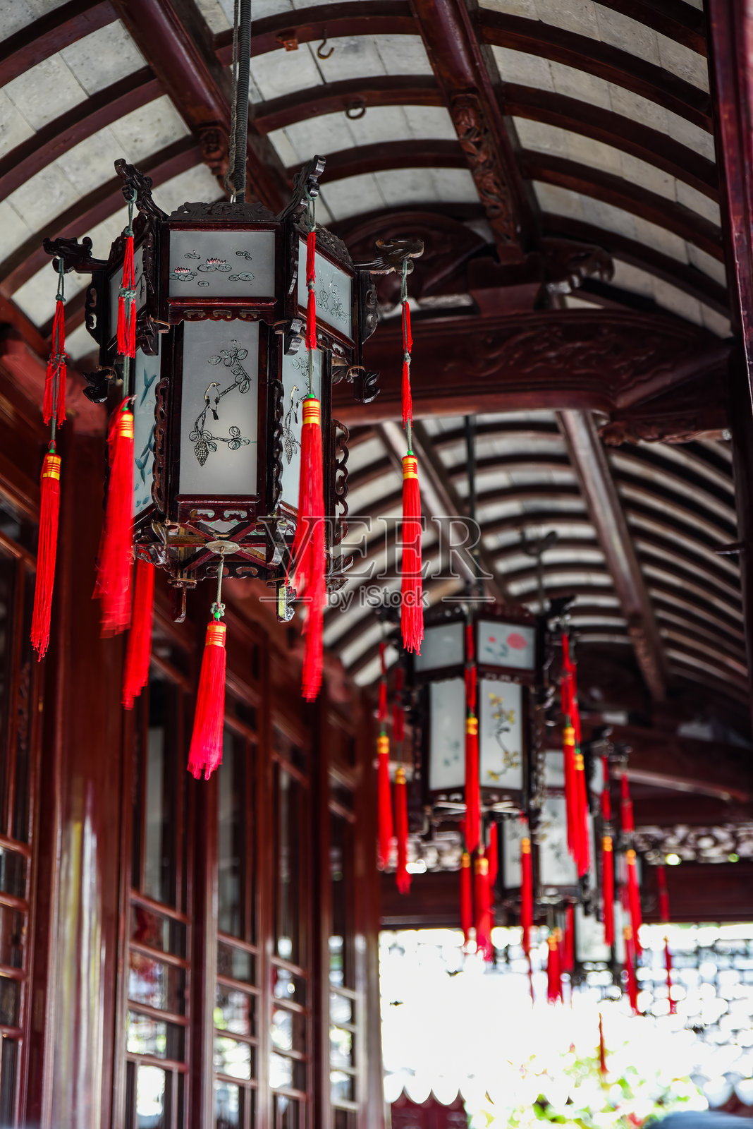 上海著名历史遗址豫园内，红色流苏的传统中国灯笼悬挂在弯曲的木屋顶下。照片摄影图片