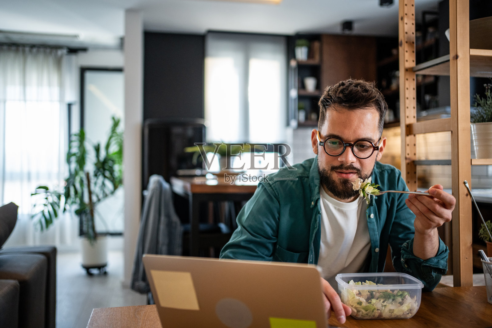 自由职业者在家吃沙拉并使用笔记本电脑工作照片摄影图片
