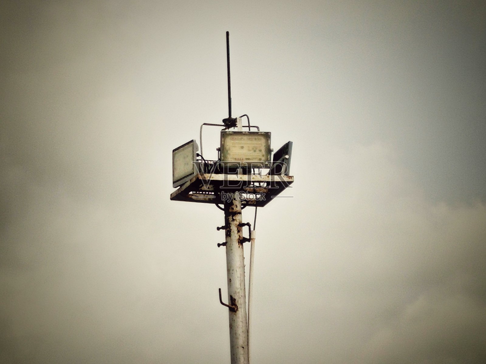 生锈的泛光灯杆与阴 cloudy 的天空照片摄影图片