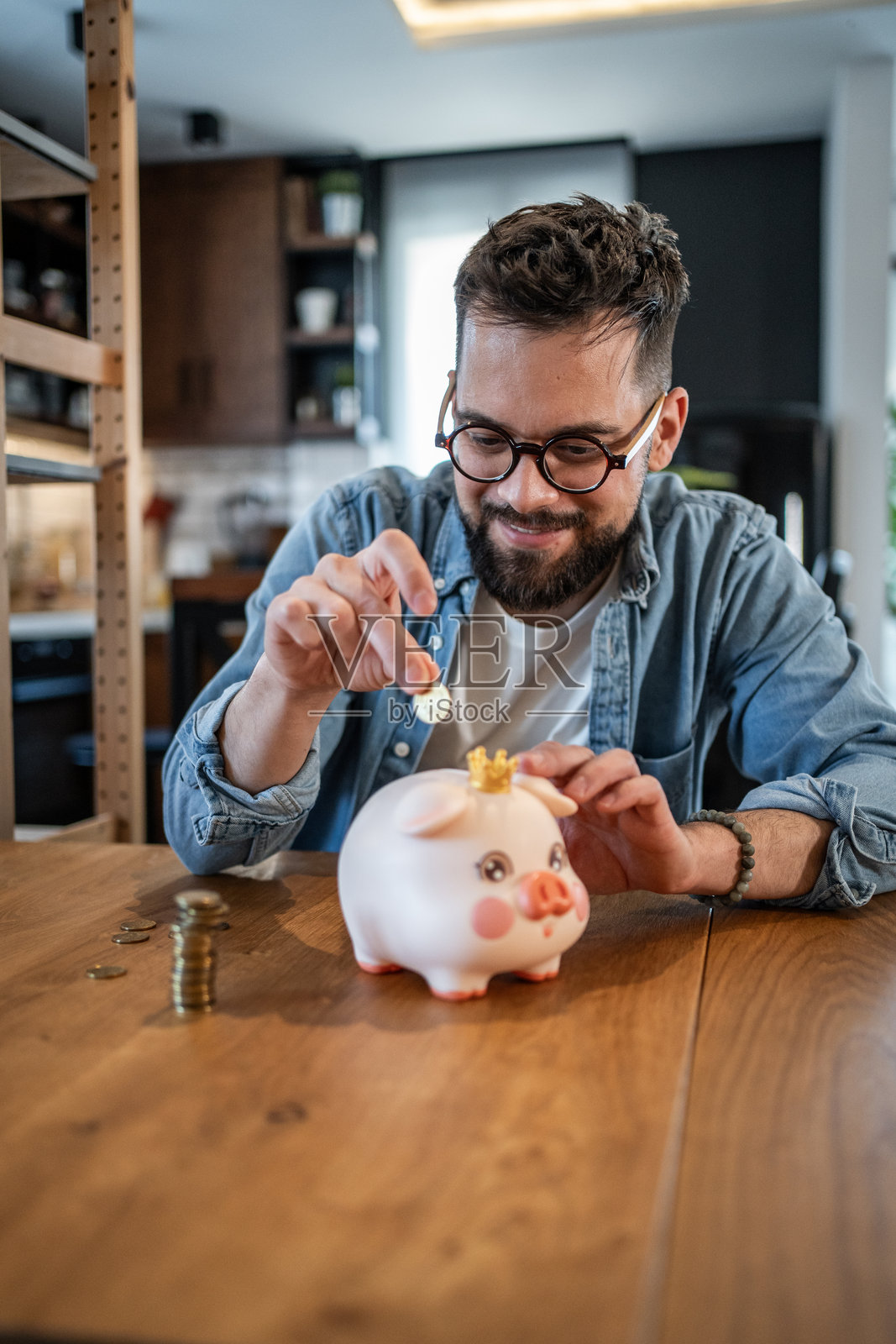 年轻男子在家里把钱存进储蓄罐照片摄影图片