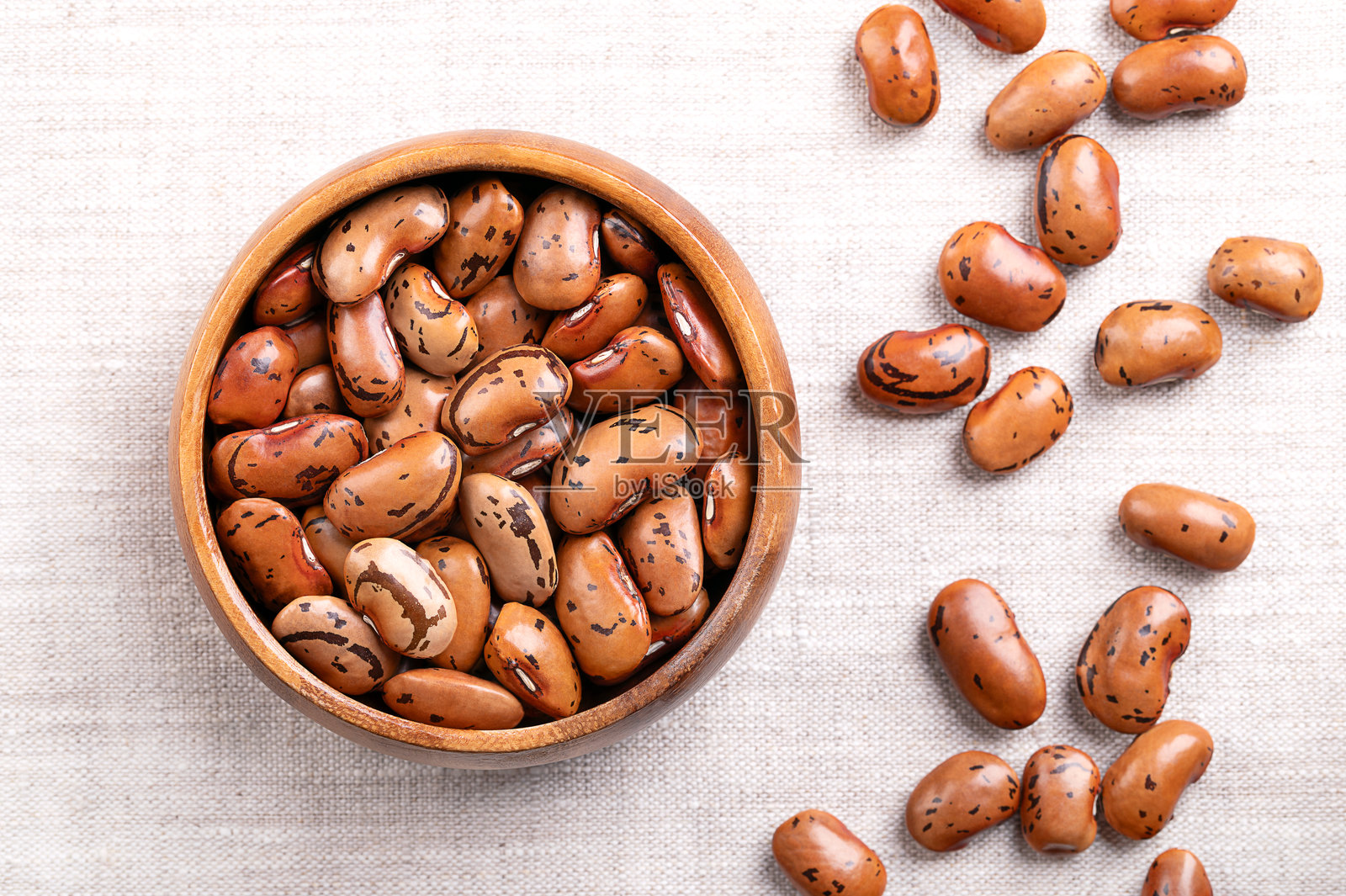 木碗中的干燥米色棕色跑豆，放在亚麻布上照片摄影图片