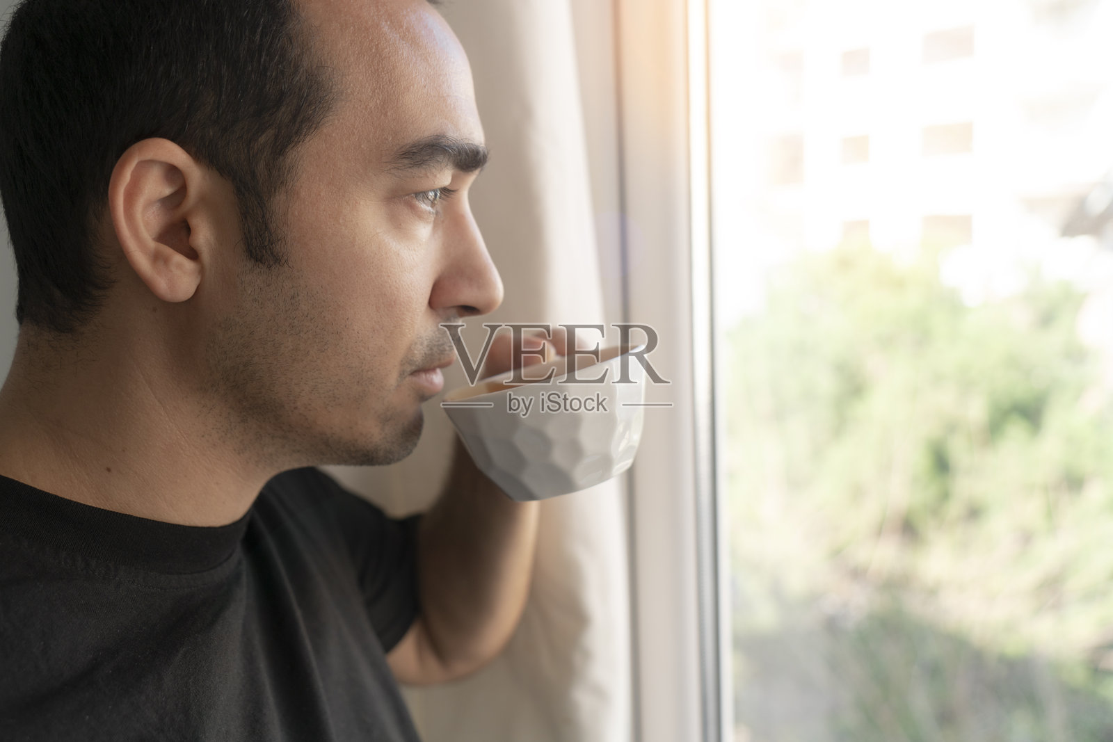 男人在家喝咖啡，望着窗外。照片摄影图片