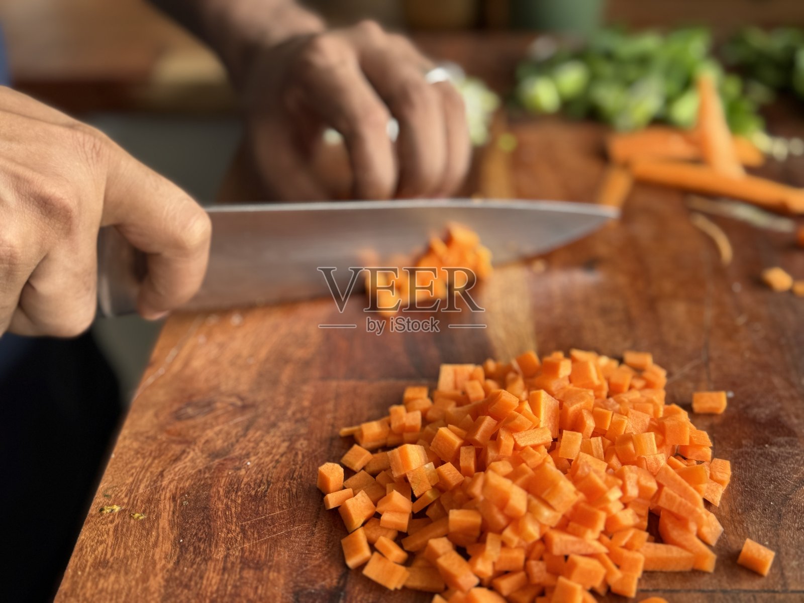 厨师在木砧板上切割胡萝卜、韭菜和洋葱 / 新鲜蔬菜切丁，自制晚餐，炖菜，砂锅菜照片摄影图片