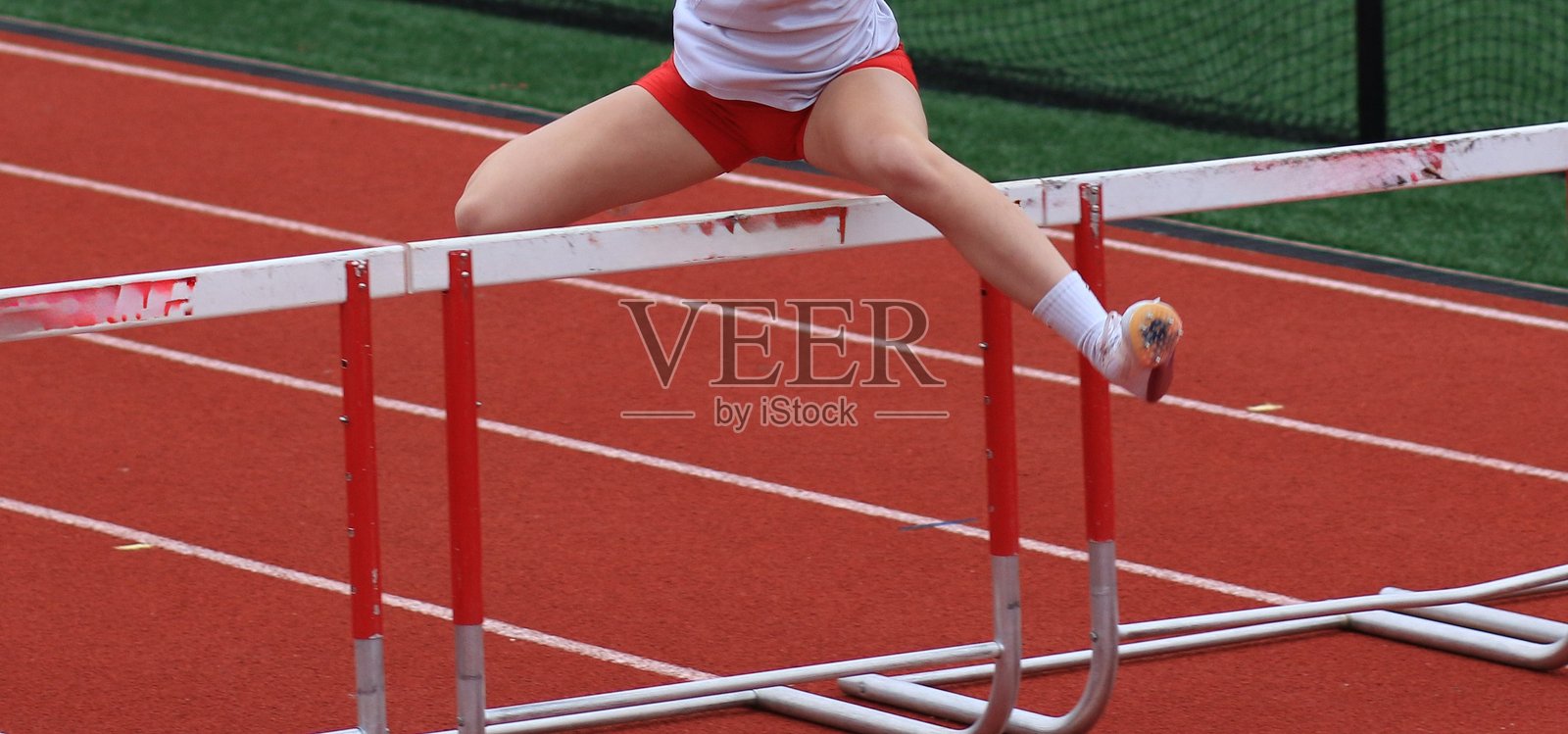 女性跑者在跨栏比赛中越过栏架照片摄影图片