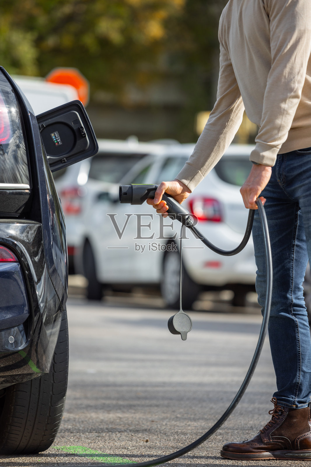 不明身份的男子在公共电动车充电站插入电动汽车充电器的特写镜头照片摄影图片