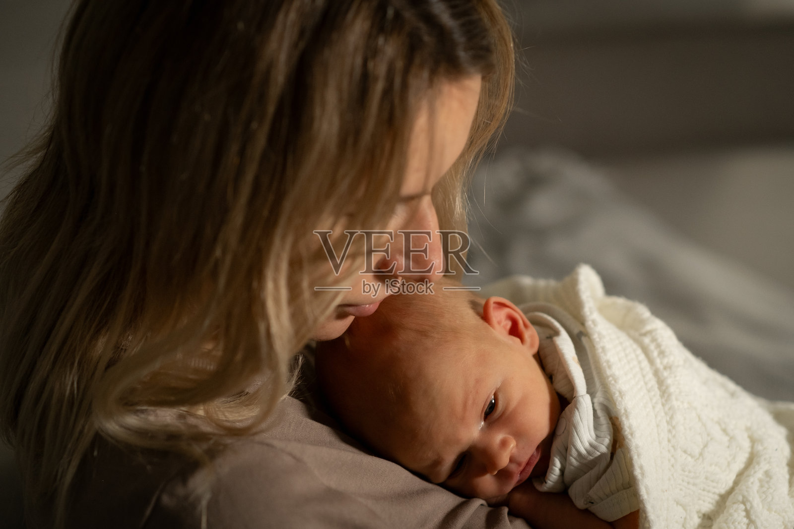 黄昏时分，母亲与婴儿在温馨宁静的房间里共享柔和的时刻，充满了温暖与爱。照片摄影图片