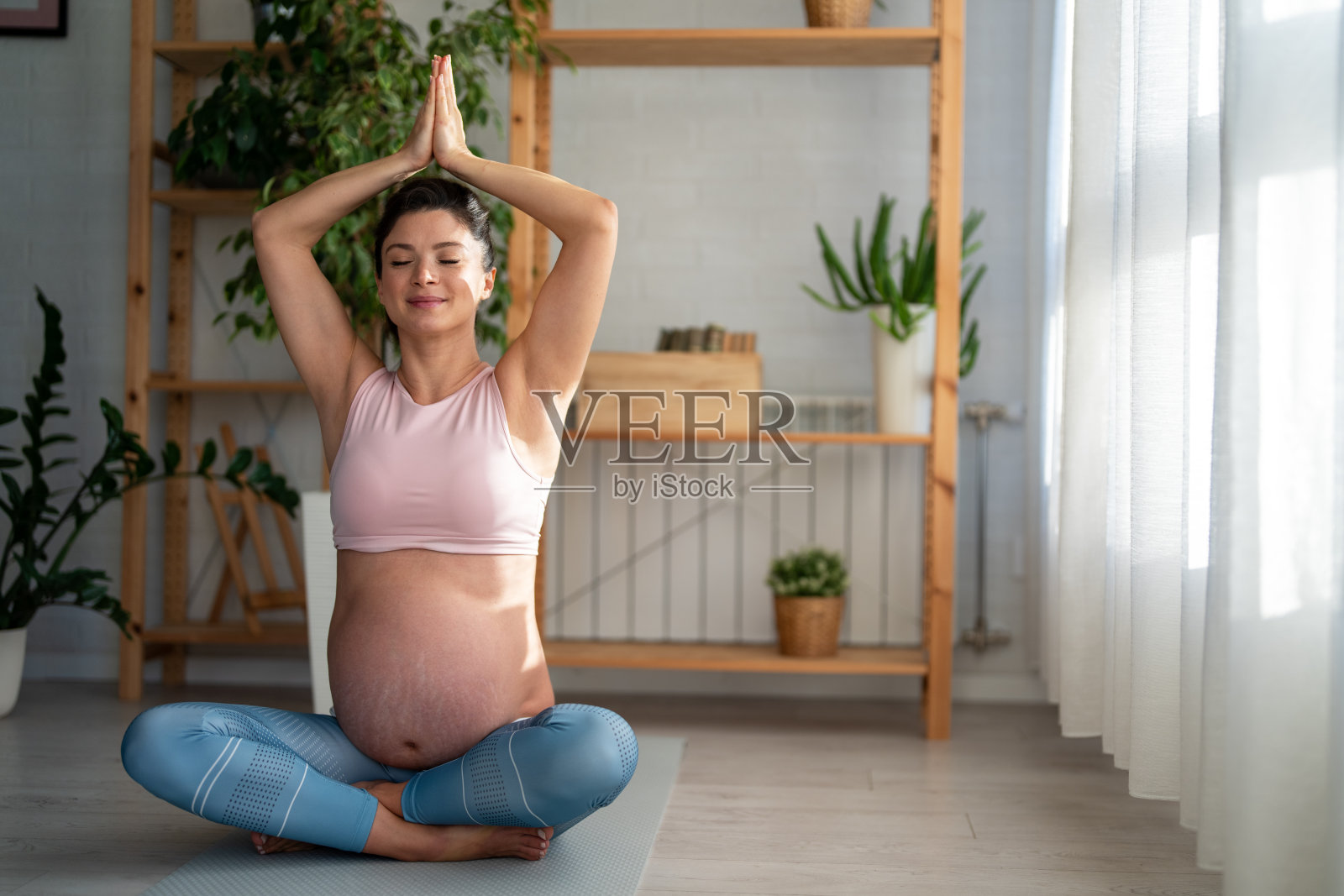 放松的孕妇在家中坐在运动垫上做呼吸练习照片摄影图片