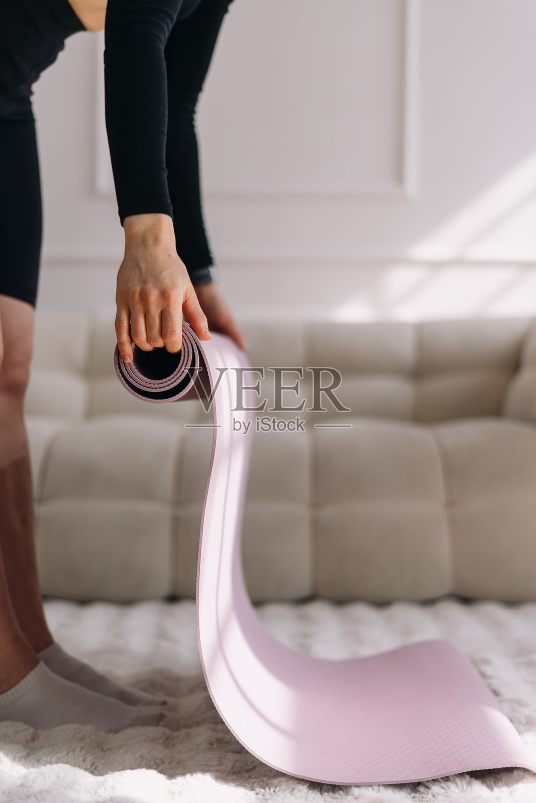 女人在完成家庭锻炼后卷起瑜伽垫照片摄影图片