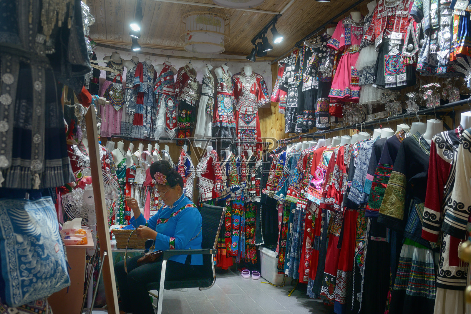 一位苗族女性在中国贵州省凯里市郎德苗寨的服装店里缝纫。照片摄影图片