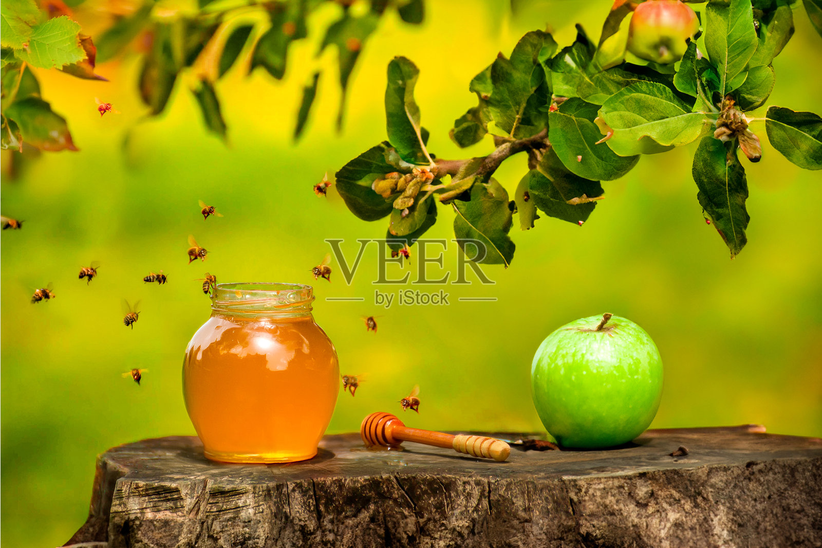 花园里树桩上的蜂蜜罐、苹果和蜜蜂照片摄影图片