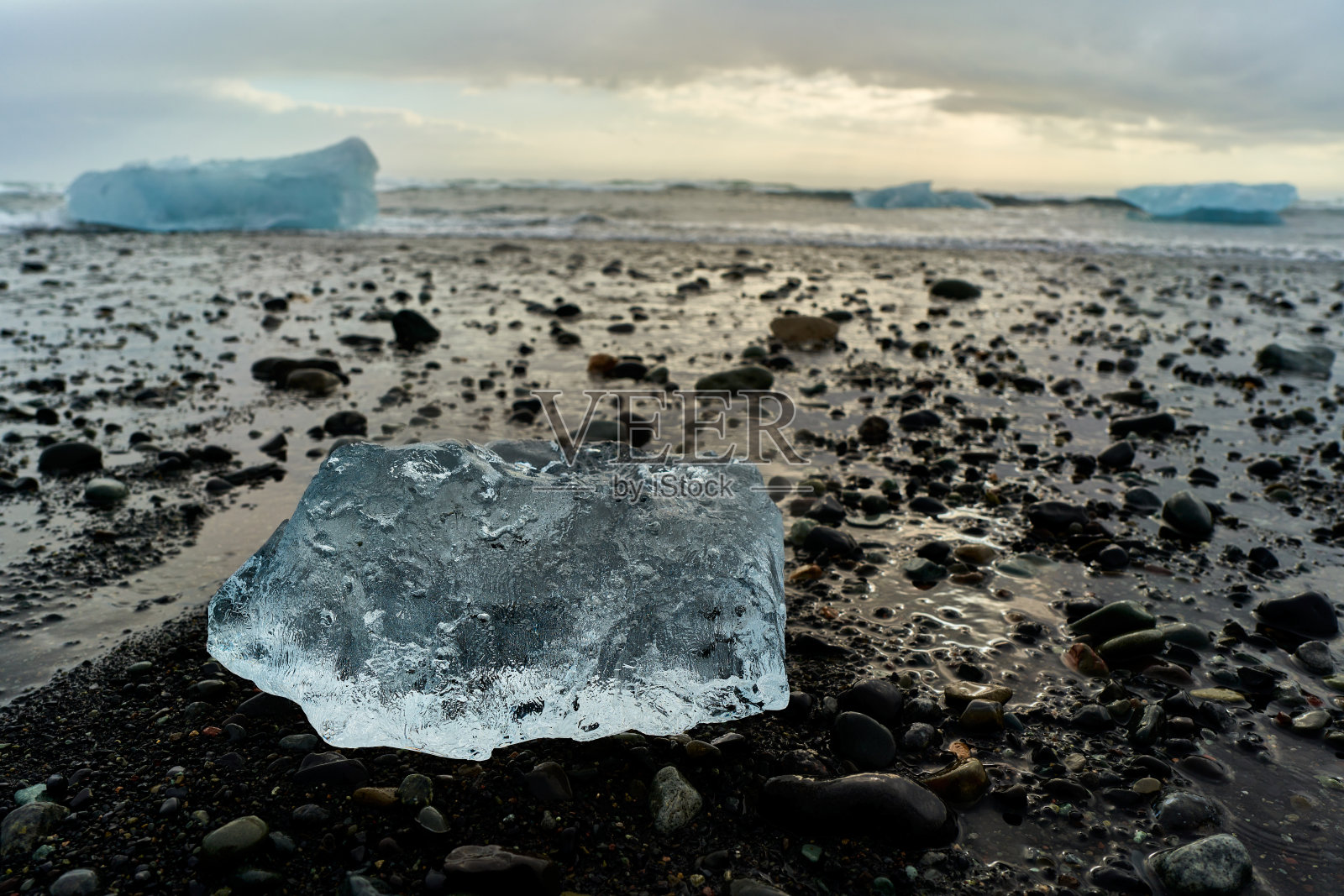 黑沙滩上融化的冰块，背景是冰山照片摄影图片