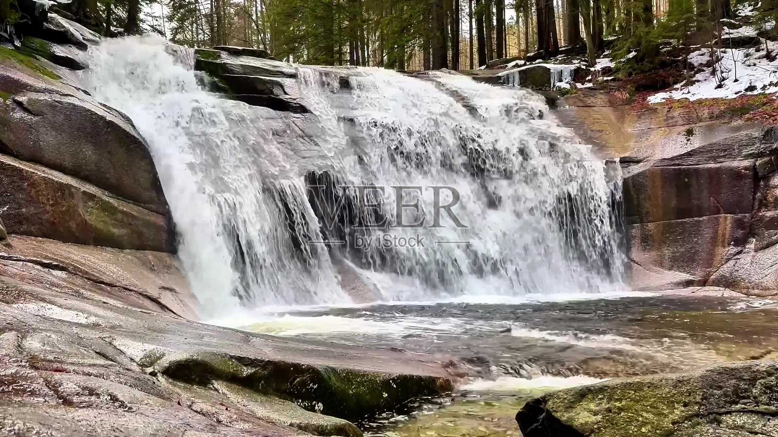一座美丽的瀑布优雅地流淌在郁郁葱葱的森林景观中，充满宁静。照片摄影图片