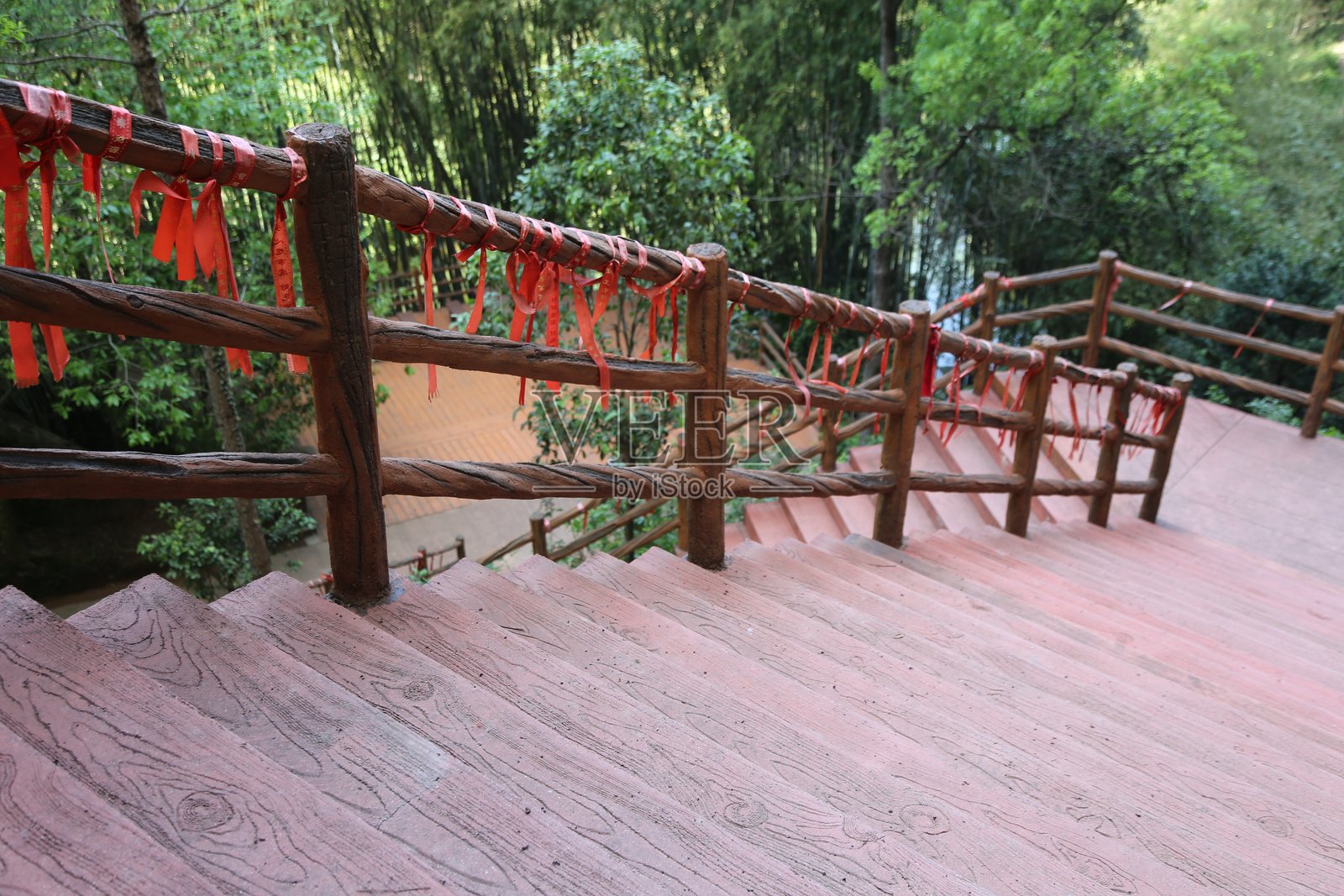 户外楼梯的木质扶手上缠绕着红色布条，背后是竹林。照片摄影图片