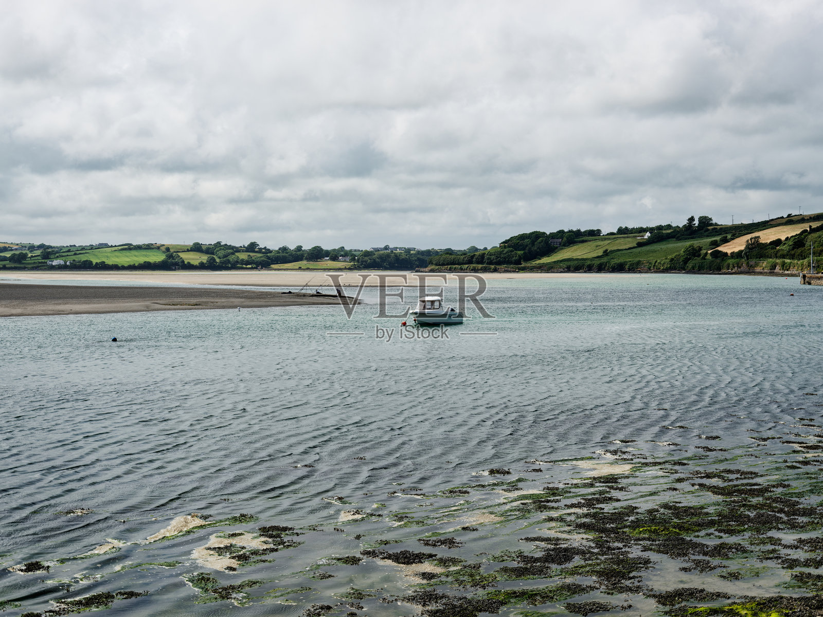 在爱尔兰的中环湾海滩探索，享受宁静水域中船只的美丽景色和郁郁葱葱的山丘。照片摄影图片