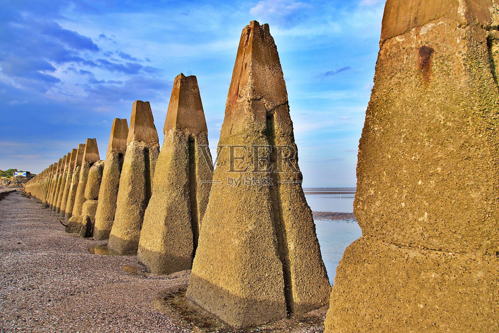 在绚丽的天空下的混凝土海防设施。照片摄影图片