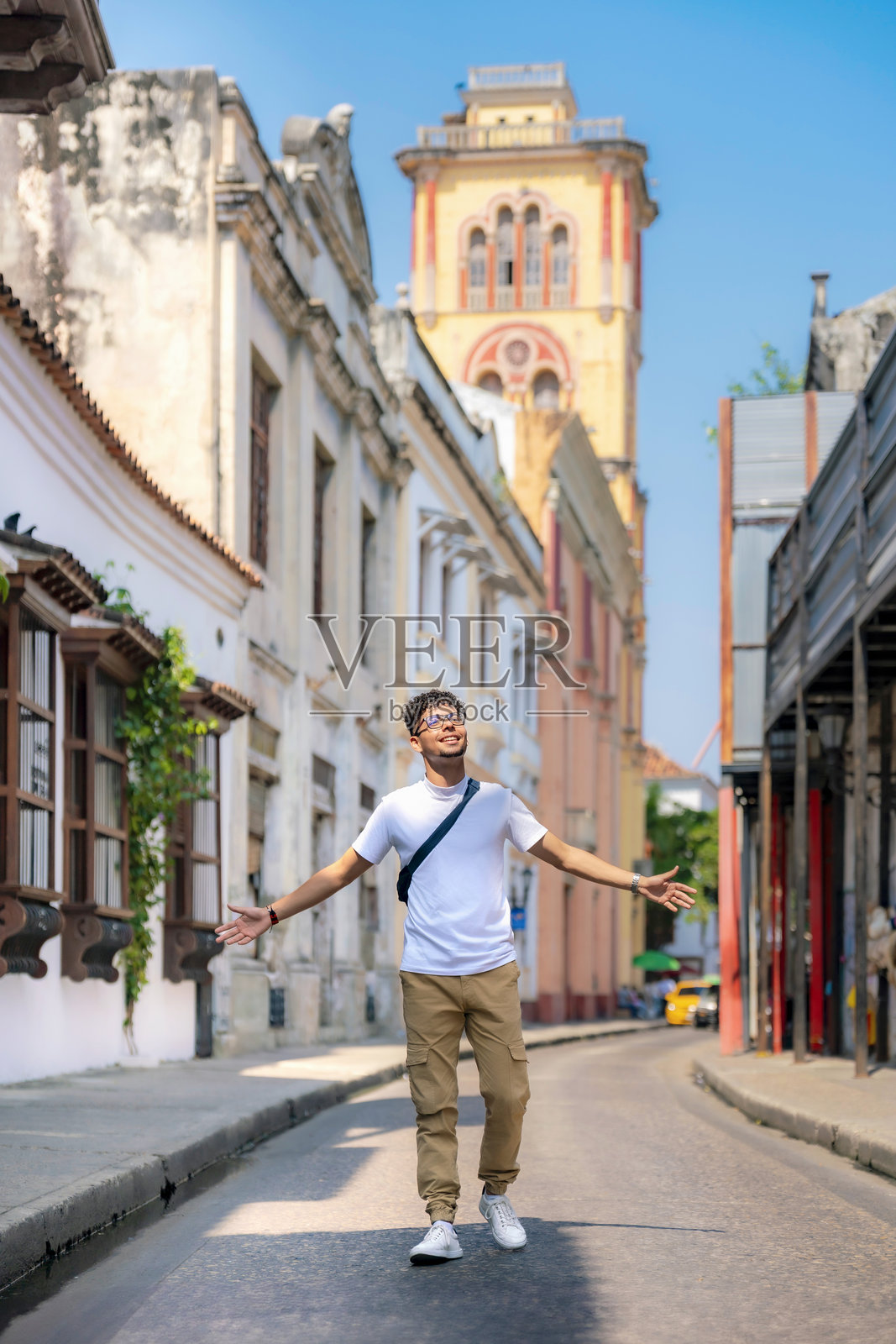 微笑的年轻拉丁裔男子在哥伦比亚卡塔赫纳的街道上悠闲地走着照片摄影图片
