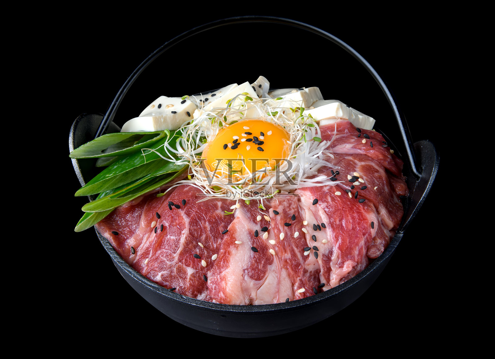 生牛肉寿喜锅，配有鸡蛋、豆腐、蘑菇和蔬菜照片摄影图片