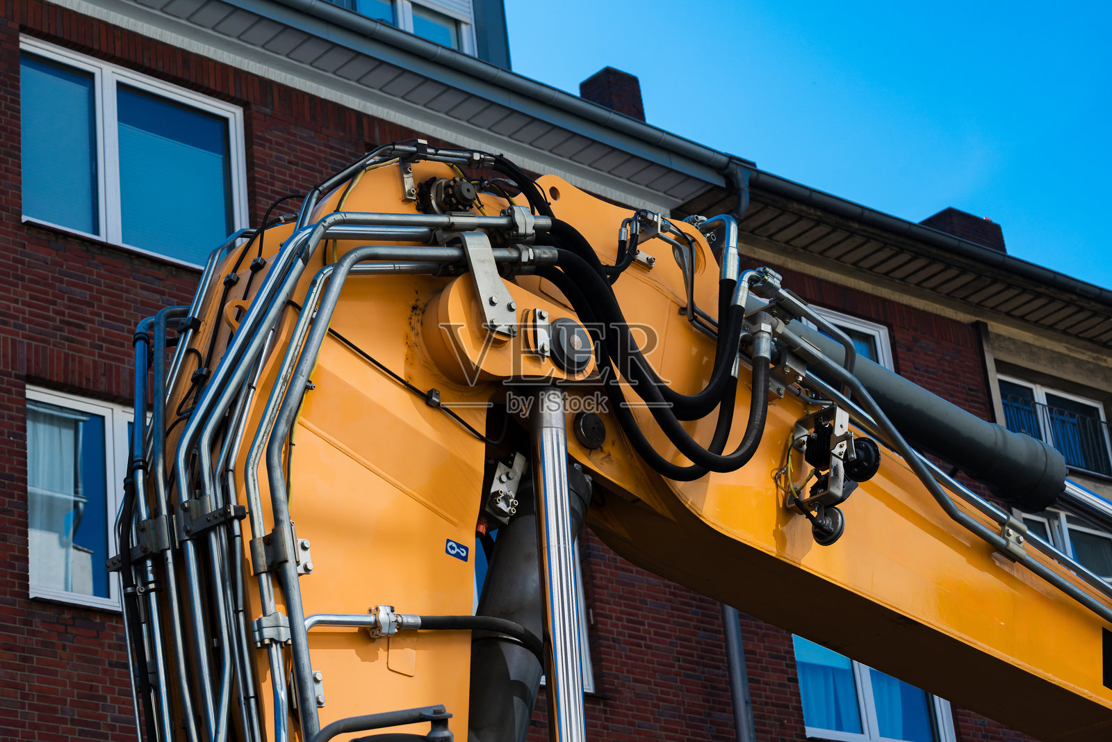 挖掘机在蓝天下的城市建筑附近作业照片摄影图片