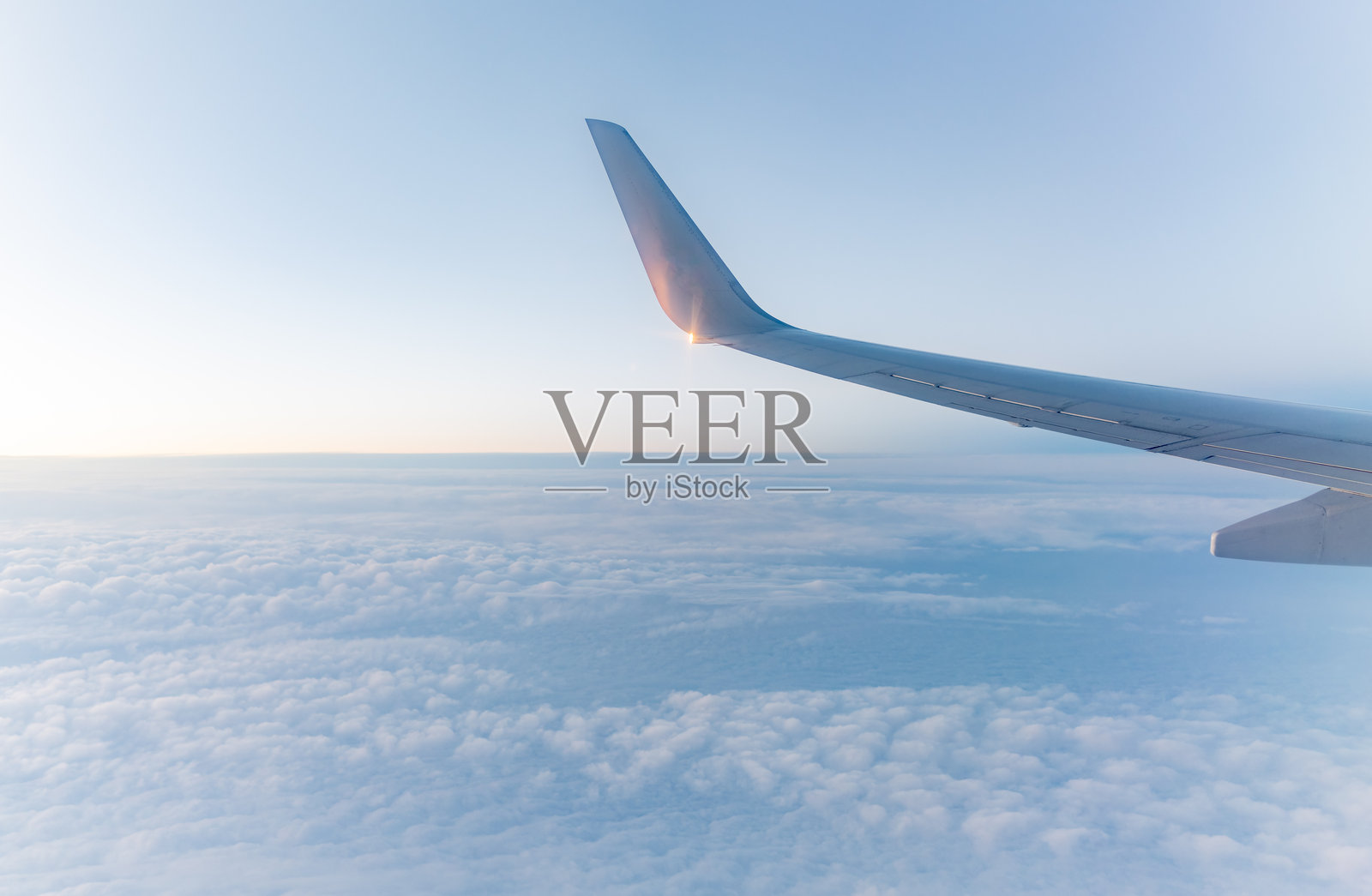 美丽的鲑鱼色黎明和云层上方的飞机机翼。照片摄影图片