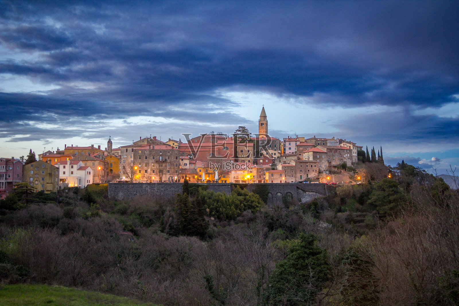克罗地亚拉宾市的日落景色，暴风雨的日子，城市灯光闪烁。照片摄影图片