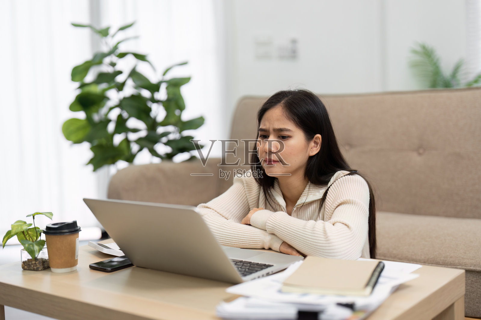 专注与挑战。一位女性沉思地看着她的笔记本电脑，思考着她的工作。照片摄影图片