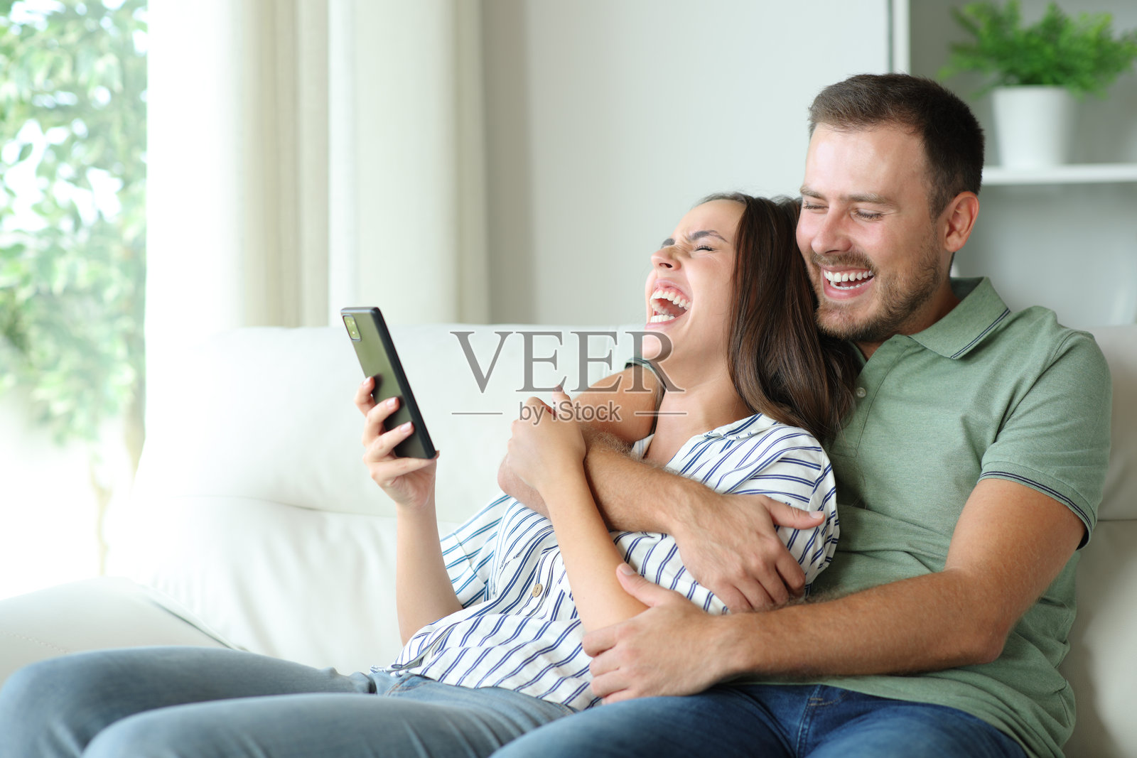 快乐的情侣大声笑着查看手机照片摄影图片