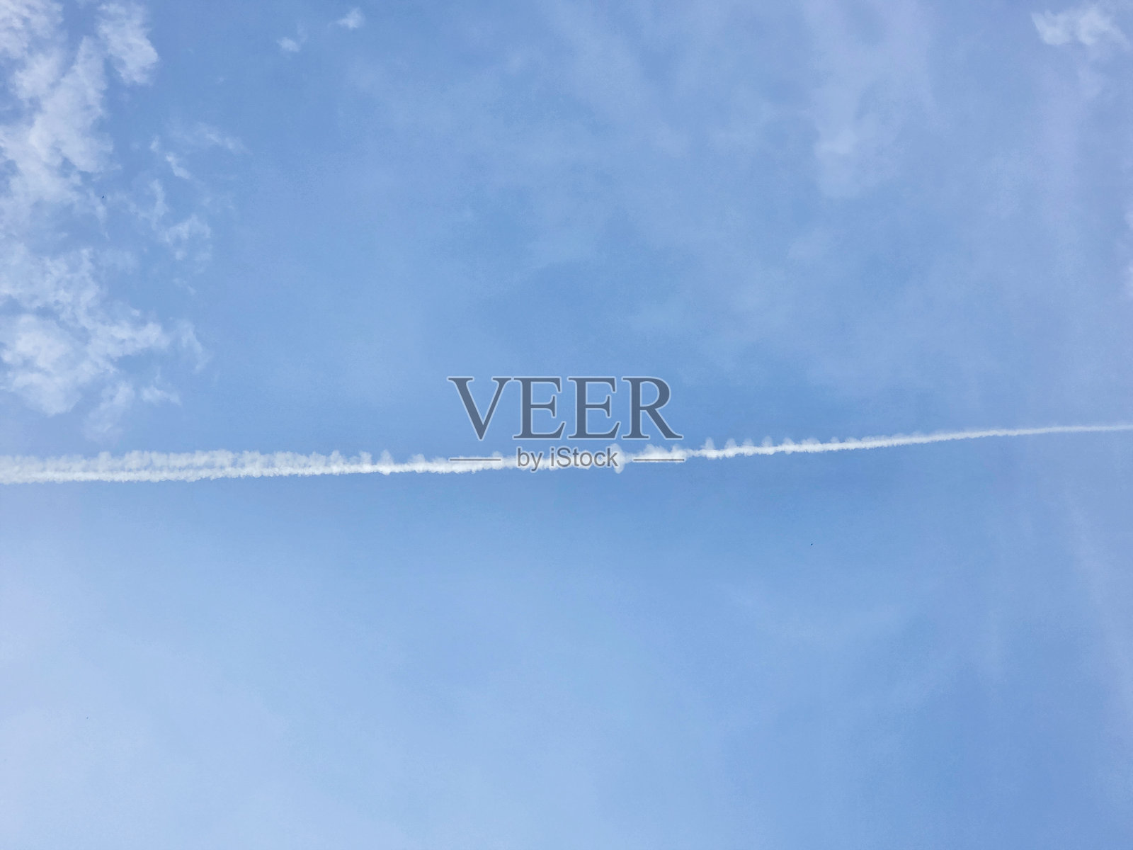 一条轻盈的飞机尾迹在晴朗的蔚蓝天空中延伸。照片摄影图片