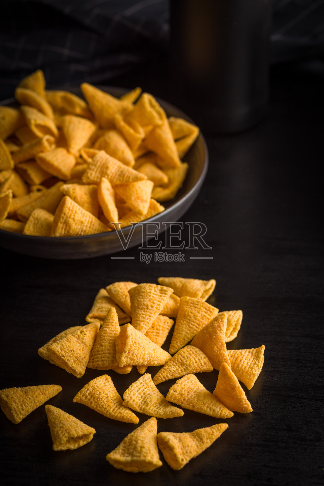 黑色桌子上的咸味零食薯片。照片摄影图片